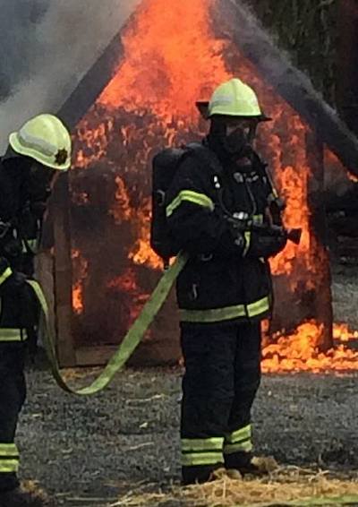 To brandbekæmpere i uniform, som er ved at slukke brand