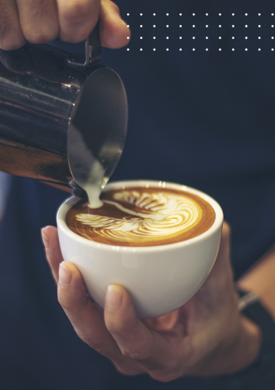 en kop cappucino tilberedes. Den skummede mælk hældes i som en mønster