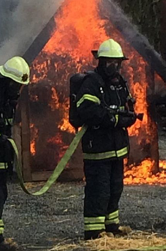 To brandbekæmpere i uniform, som er ved at slukke brand