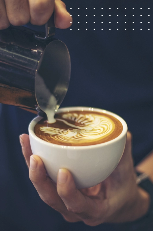 en kop cappucino tilberedes. Den skummede mælk hældes i som en mønster