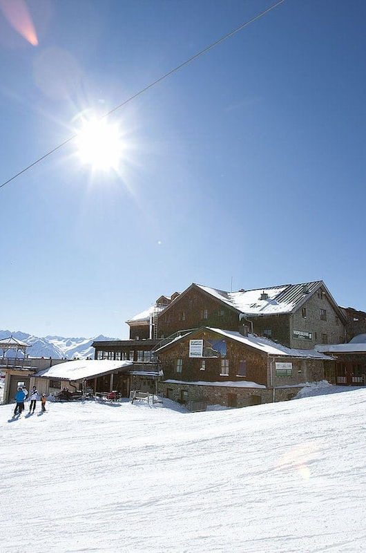 skilandskab med hytte i baggrunden. Skilift i grøn kan ses passere